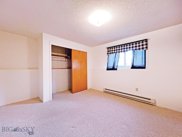 unfurnished bedroom featuring baseboard heating, carpet floors, a textured ceiling, and a closet