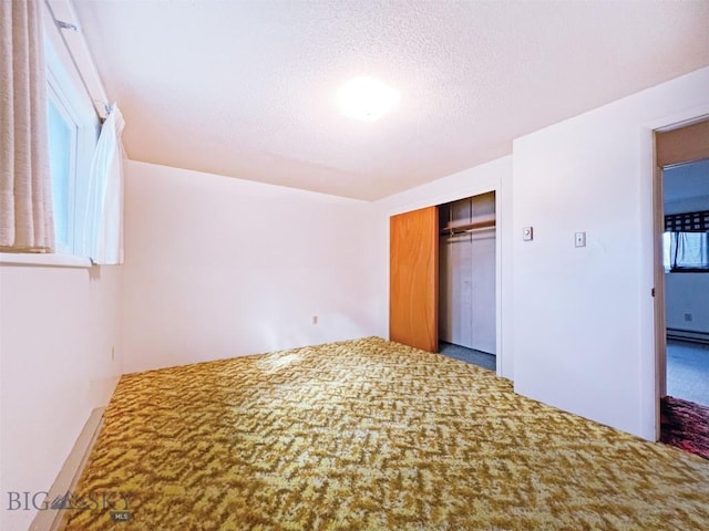unfurnished bedroom featuring multiple windows, carpet flooring, a closet, and a textured ceiling