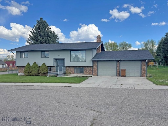 split foyer home featuring an attached garage, driveway, a chimney, and a front yard