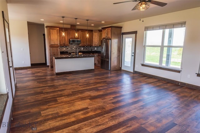 kitchen with appliances with stainless steel finishes, dark countertops, backsplash, ceiling fan, and dark wood-style floors