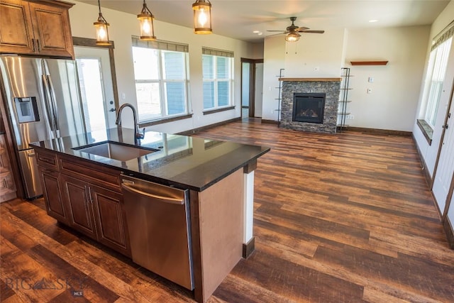 kitchen featuring appliances with stainless steel finishes, a sink, healthy amount of natural light, and a stone fireplace