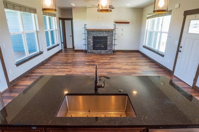 kitchen with a sink, wood finished floors, baseboards, and a fireplace