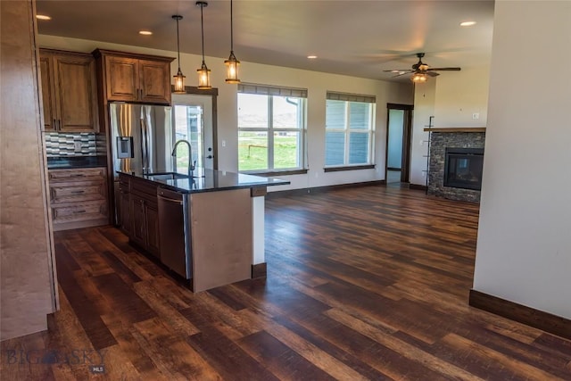 kitchen with stainless steel dishwasher, a sink, dark wood finished floors, open floor plan, and recessed lighting