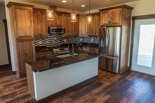 kitchen with appliances with stainless steel finishes, a sink, decorative backsplash, dark wood-style flooring, and brown cabinetry