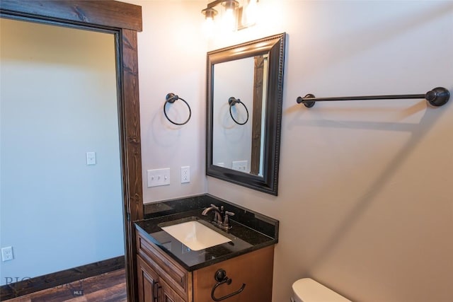 half bath with vanity, toilet, and wood finished floors