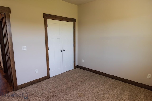 unfurnished bedroom featuring dark carpet, baseboards, and a closet