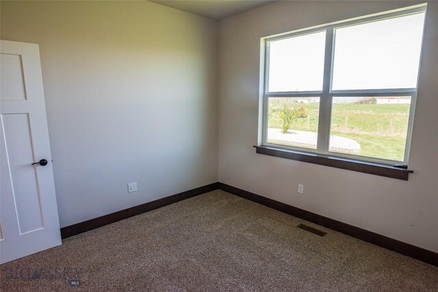 unfurnished room with dark colored carpet and baseboards