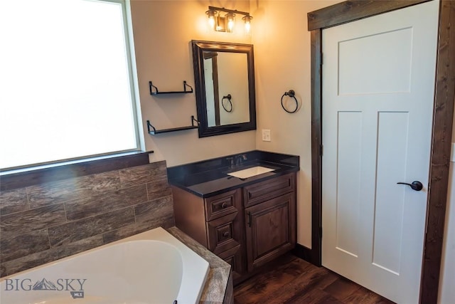 bathroom featuring a bath, wood finished floors, and vanity