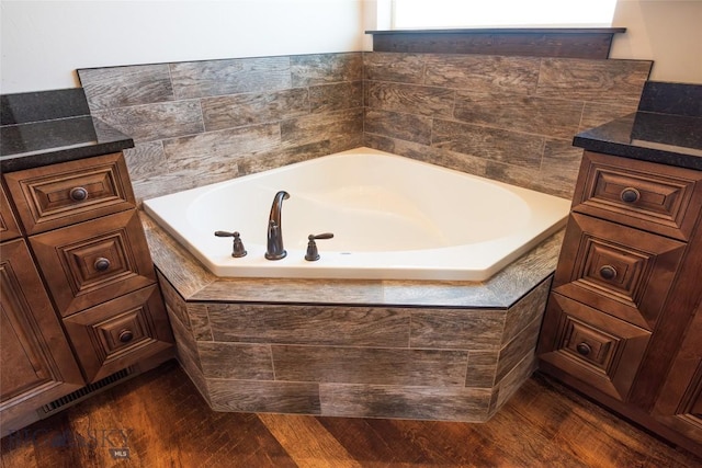full bath with a bath and wood finished floors