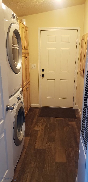 225 N Geyser St, West Yellowstone, MT 59758 - washroom featuring stacked washing machine and dryer, cabinet space, dark wood-type flooring, a heating unit, and baseboards