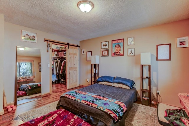 1816 S Rouse Unit 1 & 2, Bozeman, MT 59715 - bedroom featuring a barn door, a textured ceiling, wood finished floors, a walk in closet, and a closet