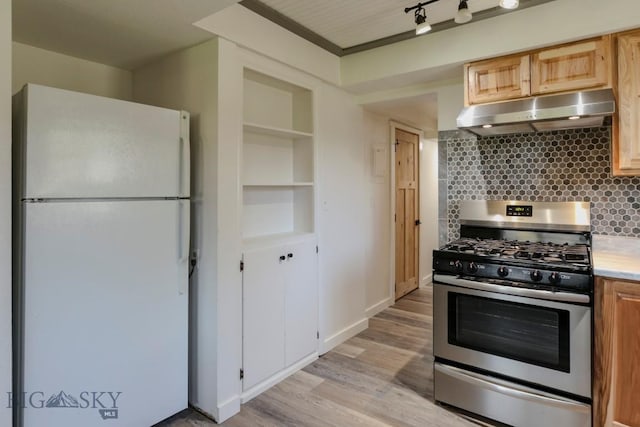 1816 S Rouse, Bozeman, MT 59715 - kitchen with freestanding refrigerator, stainless steel gas stove, under cabinet range hood, backsplash, and light wood-type flooring