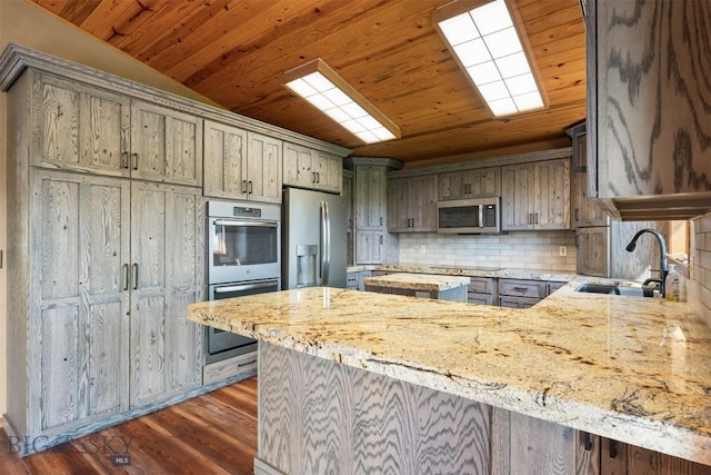 kitchen with stainless steel appliances, a sink, wooden ceiling, backsplash, and light stone counters