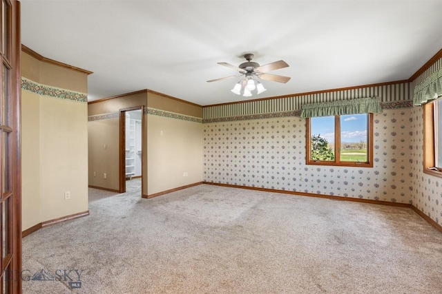 empty room with carpet, ceiling fan, baseboards, and crown molding