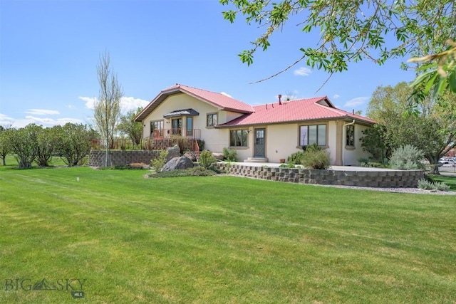 back of property with a yard, stucco siding, and metal roof