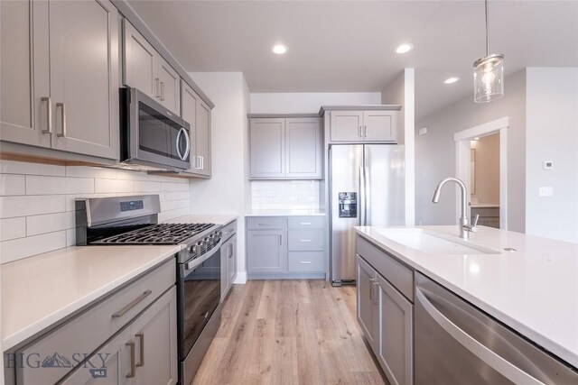 440 Meriwether Ave, Bozeman, MT 59718 - kitchen with stainless steel appliances, a sink, gray cabinetry, light wood-type flooring, and light countertops