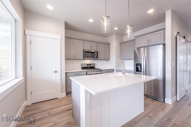 440 Meriwether Ave, Bozeman, MT 59718 - kitchen with appliances with stainless steel finishes, gray cabinetry, a sink, light wood finished floors, and decorative backsplash