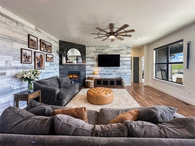 living room with a stone fireplace, ceiling fan, wood finished floors, recessed lighting, and baseboards