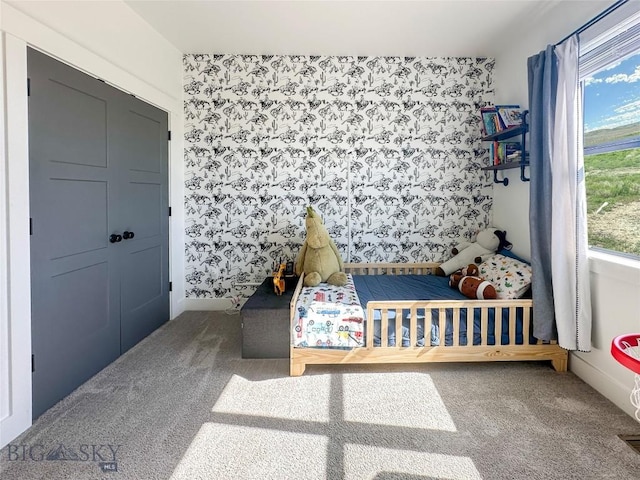 carpeted bedroom featuring wallpapered walls and baseboards