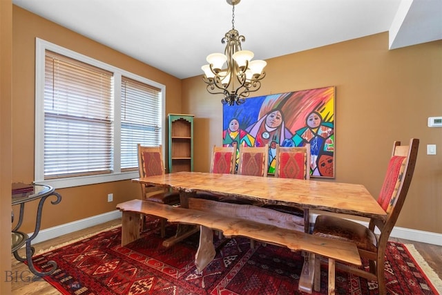 dining room featuring a chandelier, baseboards, and wood finished floors