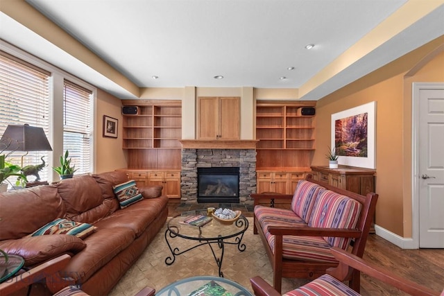 living area with baseboards, wood finished floors, and a stone fireplace