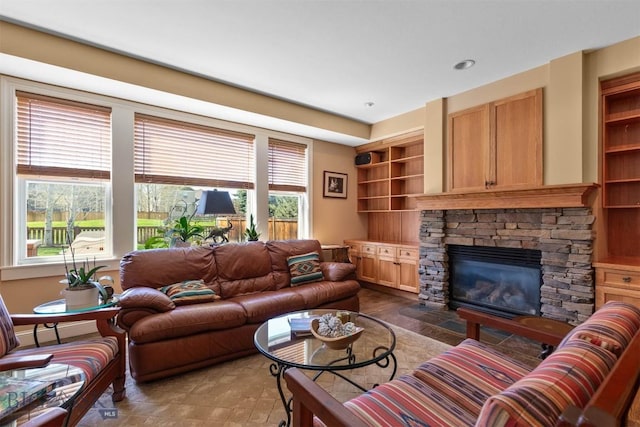 living area featuring a stone fireplace and built in shelves
