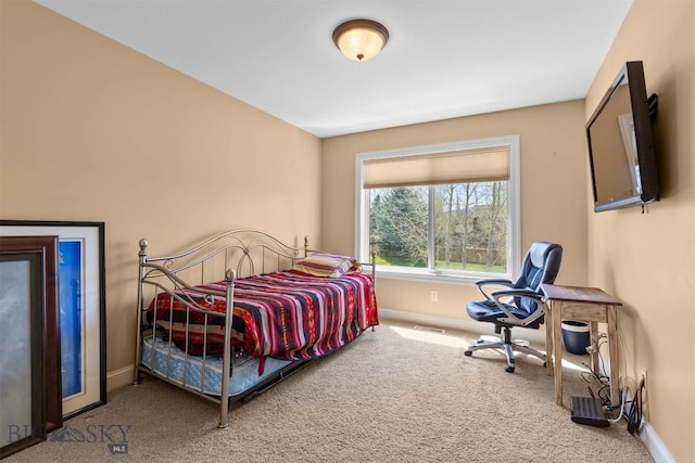 carpeted bedroom with baseboards and a desk