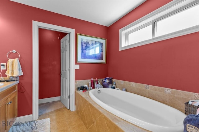 bathroom featuring a garden tub, tile patterned floors, baseboards, and vanity