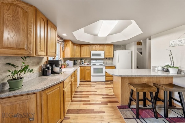 517 W Daly, Walkerville, MT 59701 - kitchen with white appliances, light wood-style floors, a peninsula, a breakfast bar, and a raised ceiling