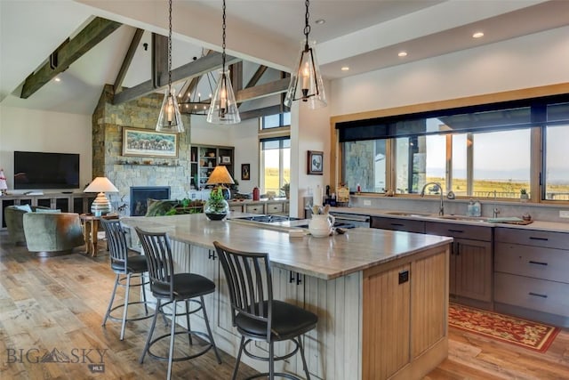 419 Upper Autumn Ridge Rd, Bozeman, MT 59715 - kitchen featuring light wood-style floors, open floor plan, beam ceiling, a fireplace, and a kitchen island