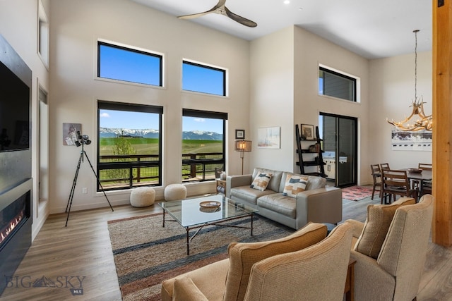 20 Prairie Falcon Ln, Belgrade, MT 59714 - living area featuring a towering ceiling, wood finished floors, ceiling fan, a warm lit fireplace, and baseboards
