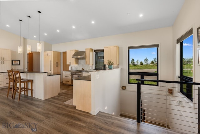 20 Prairie Falcon Ln, Belgrade, MT 59714 - kitchen featuring light brown cabinetry, wall chimney exhaust hood, dark countertops, tasteful backsplash, and dark wood-style floors
