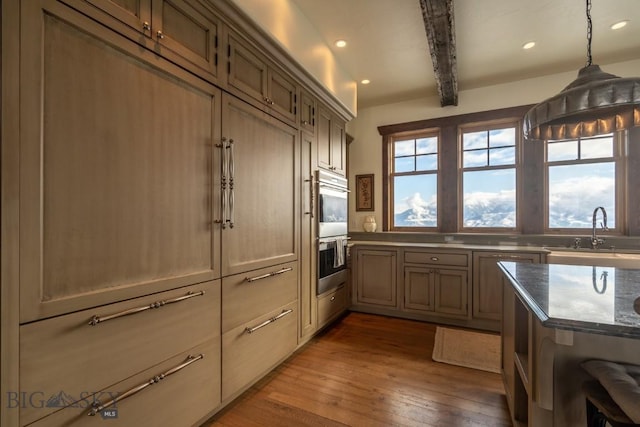 kitchen with a sink, double oven, hardwood / wood-style flooring, recessed lighting, and hanging light fixtures