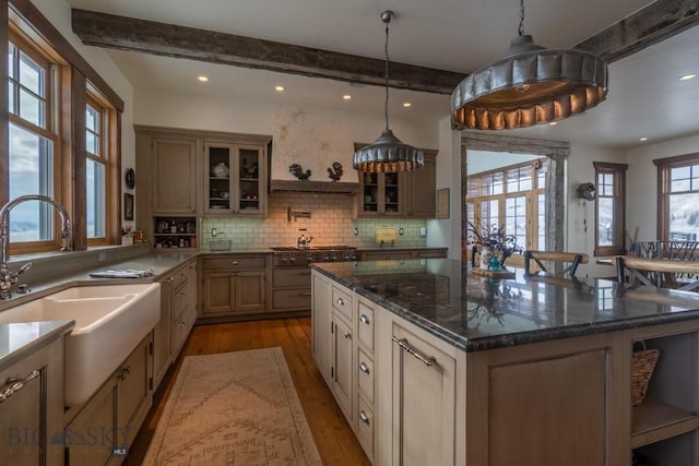 kitchen featuring a sink, beamed ceiling, wood finished floors, tasteful backsplash, and recessed lighting