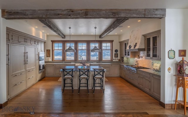 kitchen with beamed ceiling, a kitchen breakfast bar, dark wood-type flooring, plenty of natural light, and recessed lighting