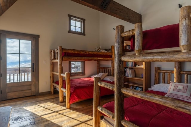 bedroom with wood finished floors, multiple windows, access to exterior, and vaulted ceiling