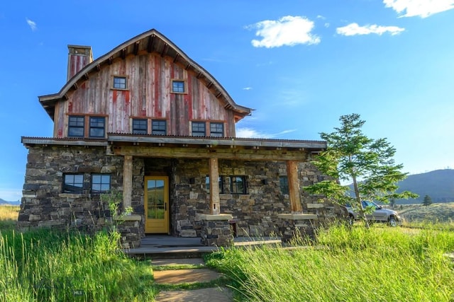 view of front of house featuring stone siding, a mountain view, and a chimney