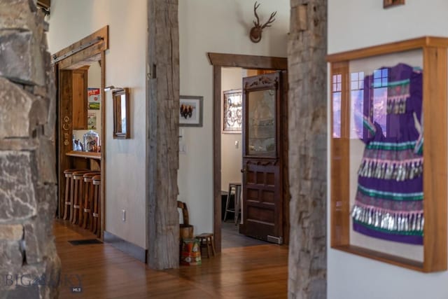 hall with wood finished floors and decorative columns