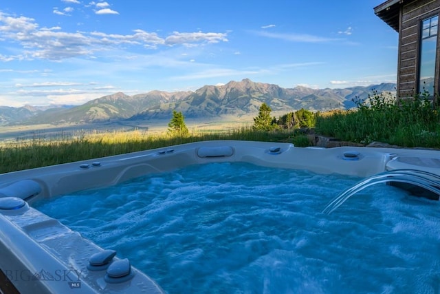 view of swimming pool with a mountain view and a hot tub