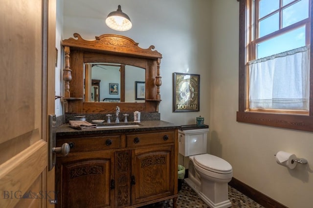 half bath featuring toilet, vanity, and baseboards