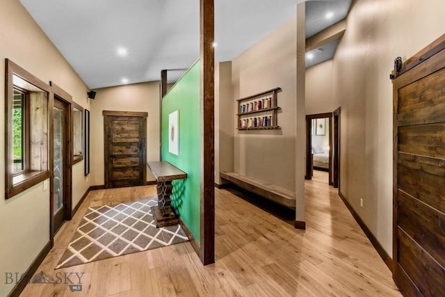 hallway featuring light wood-type flooring, baseboards, and a barn door