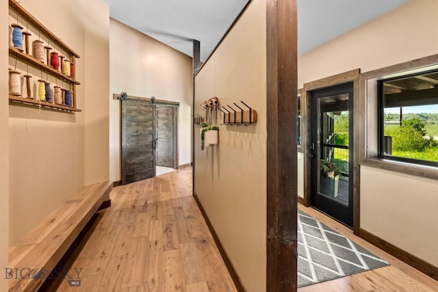 hall featuring a barn door, wood finished floors, and baseboards