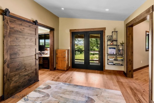 foyer entrance with french doors, plenty of natural light, wood finished floors, a barn door, and vaulted ceiling