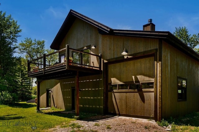 rear view of house with a chimney, a deck, and a garage