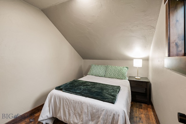 bedroom featuring lofted ceiling, hardwood / wood-style floors, and baseboards