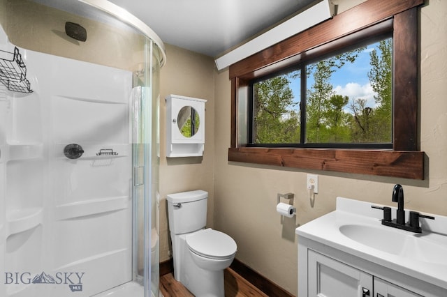bathroom with a stall shower, wood finished floors, toilet, vanity, and baseboards