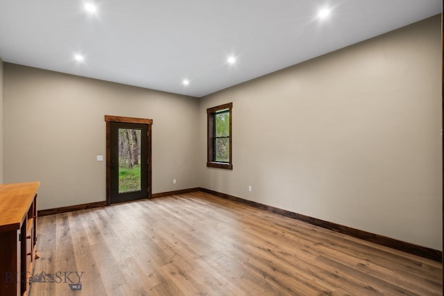 unfurnished room with wood finished floors, recessed lighting, and baseboards