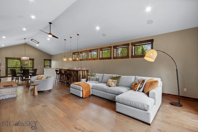 living area with light wood-style flooring, bar with sink, high vaulted ceiling, and recessed lighting