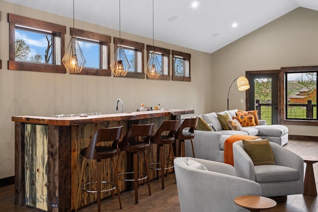 indoor wet bar with wood finished floors, high vaulted ceiling, and recessed lighting