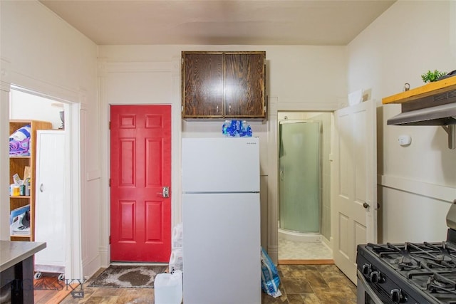 1048 S Wyoming St, Butte, MT 59701 - kitchen with freestanding refrigerator, gas stove, dark stone finish floors, under cabinet range hood, and dark brown cabinets